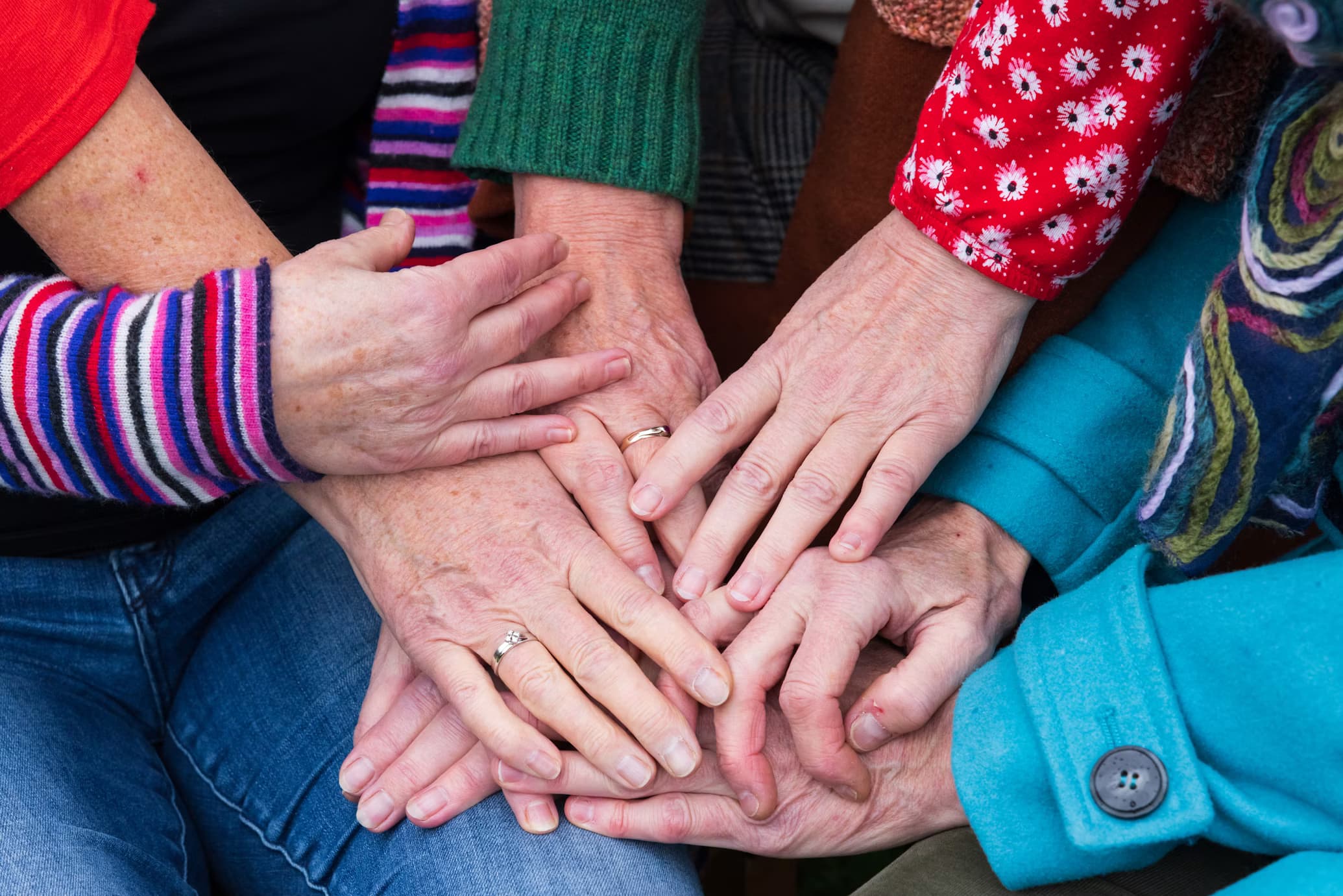 Many hands coming together to form a painted red heart